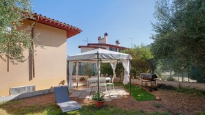 Un área de estar al aire libre cubierta con una mesa, sillas, una parrilla y una carpa.