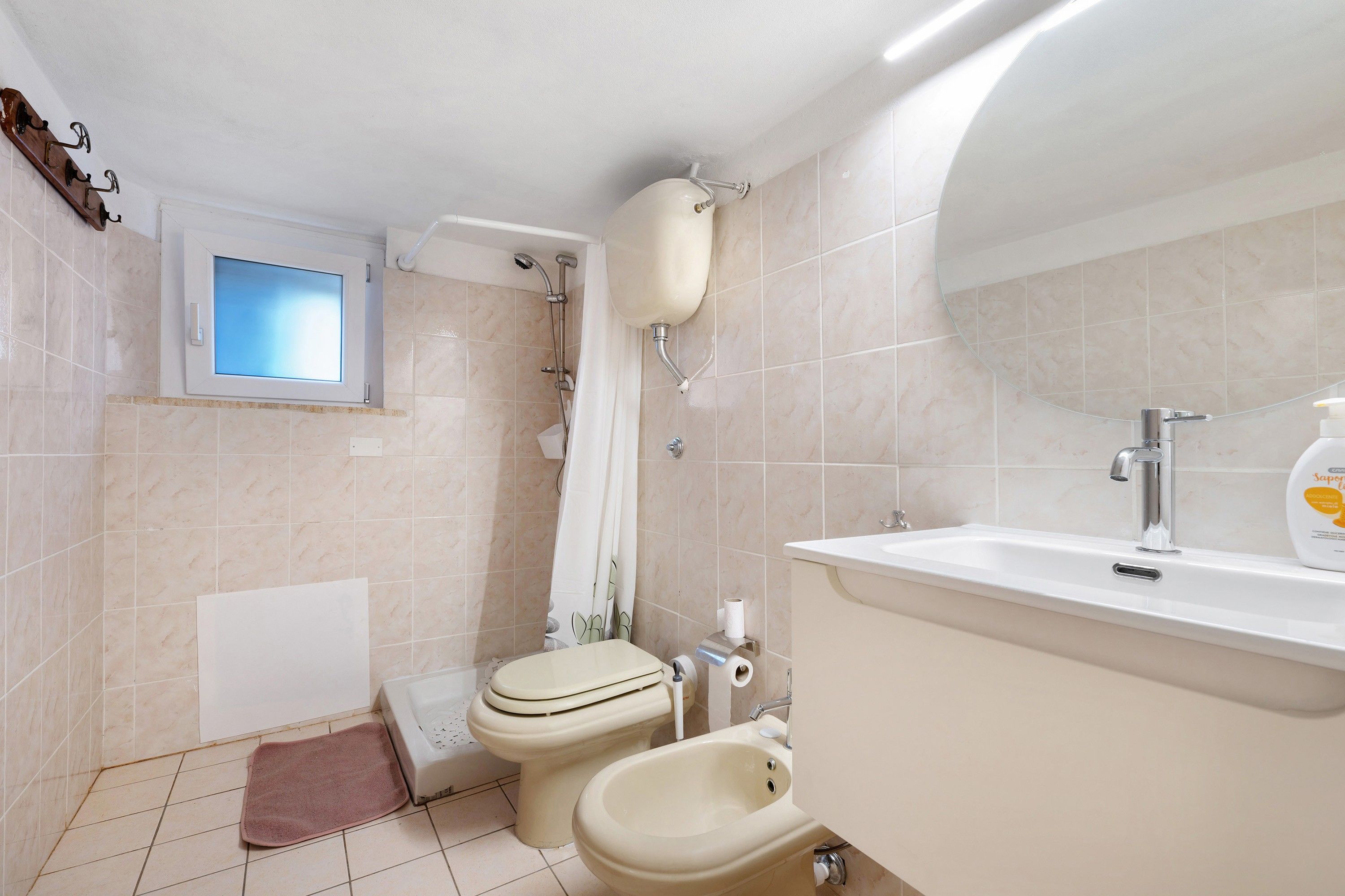Une salle de bain comprenant des toilettes, un bidet, une douche et un lavabo avec un miroir.