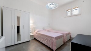 Un dormitorio con cama, armario, escritorio y ventana.