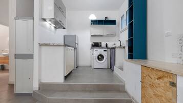 Een kleine keuken met een wasmachine, een magnetron en een inbouwoven.