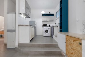 Een kleine keuken met een wasmachine, een magnetron en een inbouwoven.