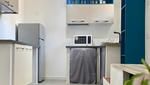 Une cuisine moderne avec des meubles blancs, un four à micro-ondes et un petit plan de travail.