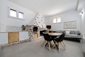 Un espace repas comprenant une cuisine aux murs en pierre, une table ronde avec des chaises et un canapé.