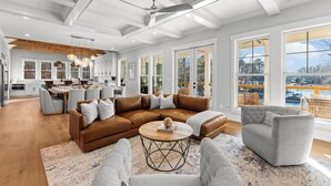 A spacious living room with a brown sectional sofa, a grey armchair, and a round coffee table. - Waterfront Estate + Dock + Pool | Game Room | Sleeps 16 | Southern Belle Estate (Mooresville)