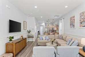 A modern living room with a sofa, armchairs, a coffee table, and a TV mounted on the wall. - Backyard + Golf Cart • Minutes to 30A + Beaches | The Little Blue Beach House (Santa Rosa Beach)