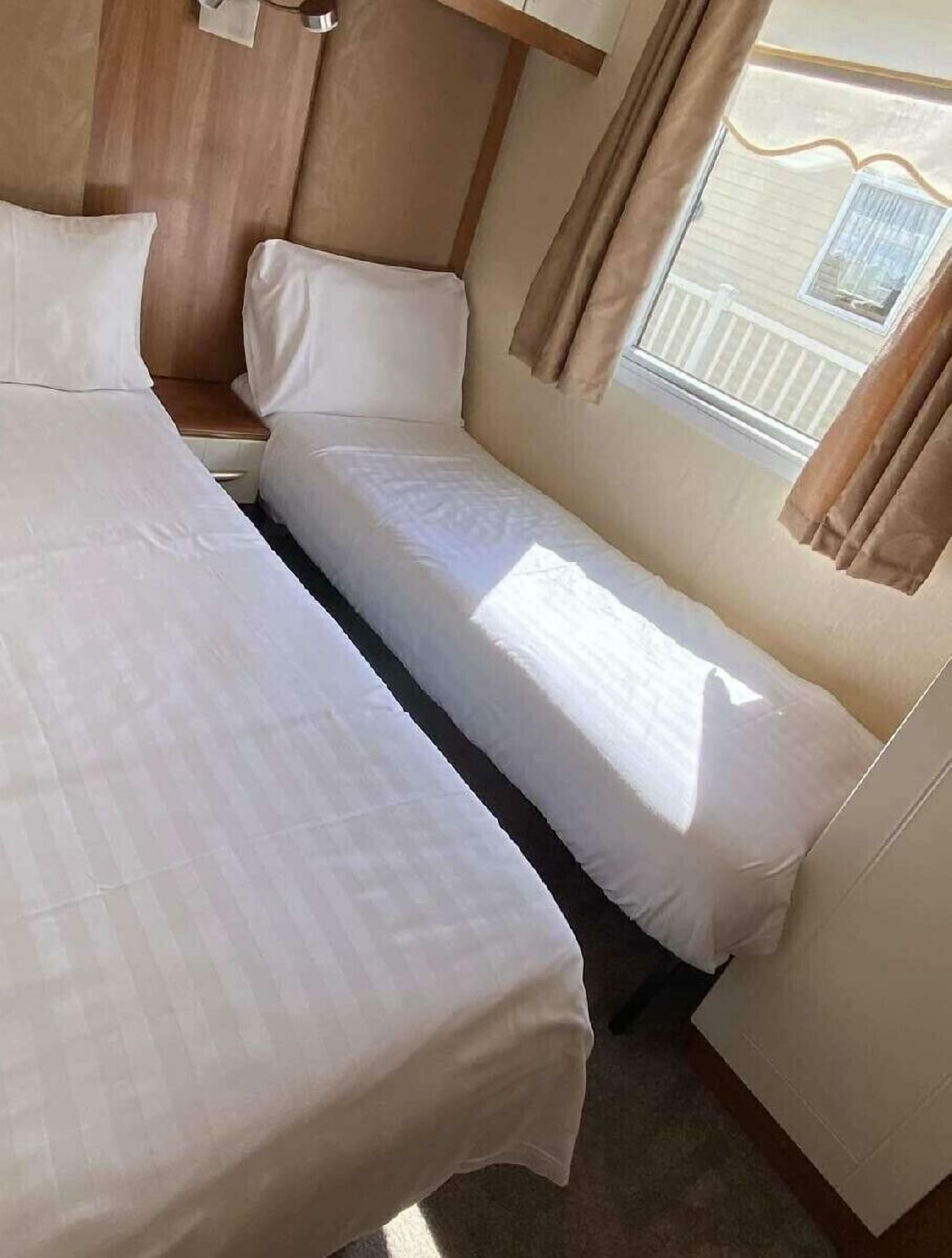 Un dormitorio con dos camas, una ventana con cortinas y vista a un edificio.