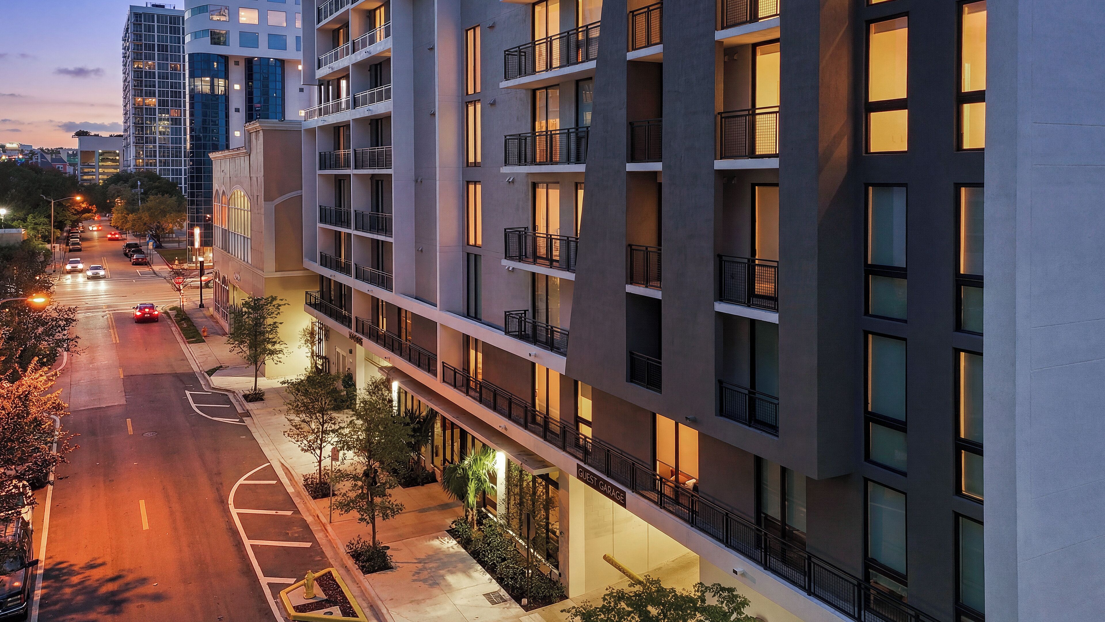 A multi-story hotel with balconies, a guest garage, and a street view.