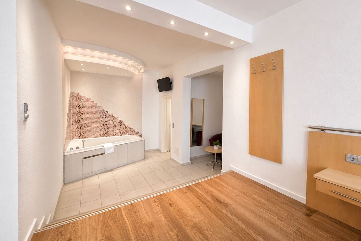 Un bagno moderno con una vasca da bagno ampia, pavimento in legno e un armadio a legno.
