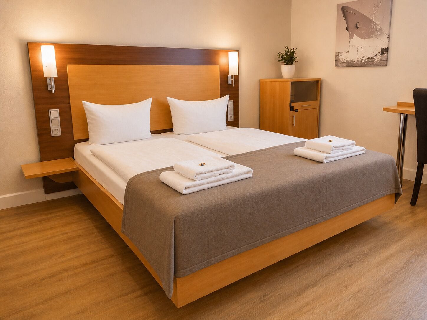 A hotel room with a large bed, bedside tables, a small cabinet, and a desk.
