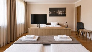 Una habitació d'hotel amb llit, televisió, escriptori, cadira i un quadre a la paret.