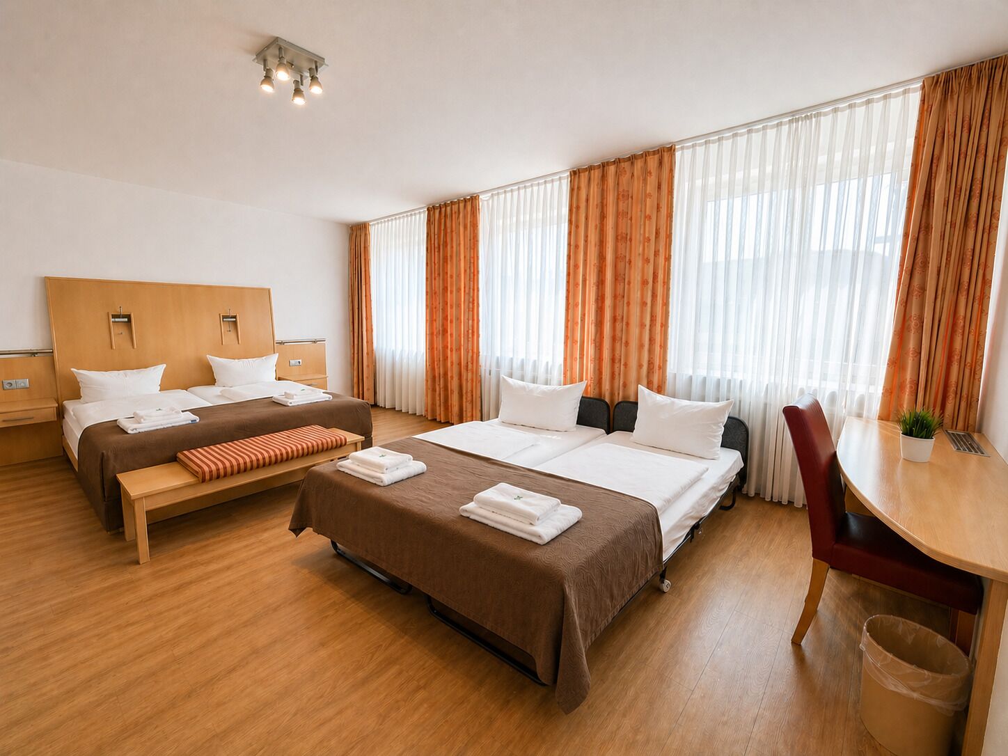 A hotel room with two beds, a desk, and a chair.