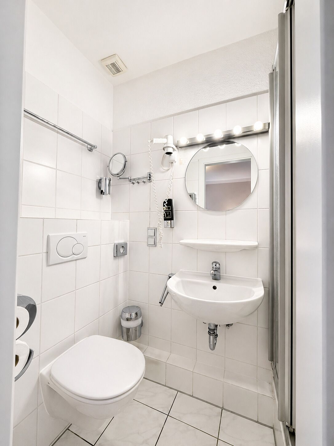 Ein modernes Badezimmer mit Toilette, Waschbecken, Spiegel und Dusche.
