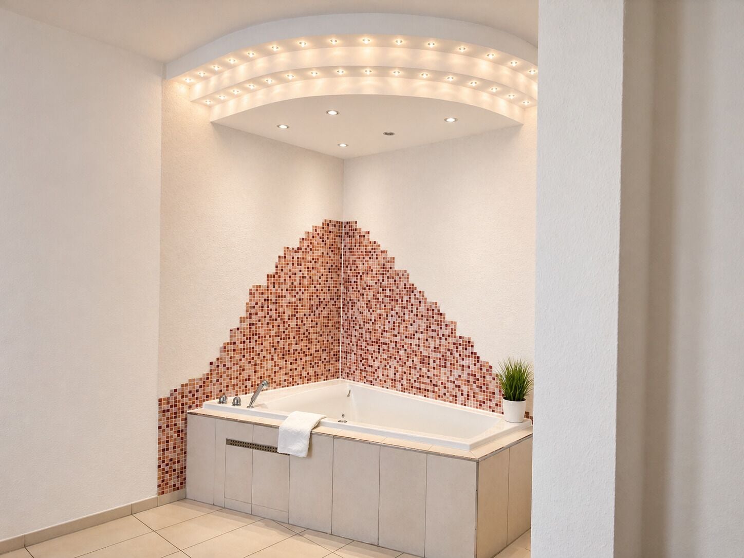 A modern bathroom with a freestanding bathtub, recessed lighting, and a mosaic tile wall.