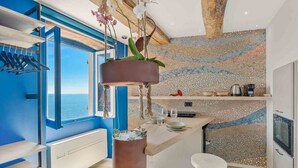 Une cuisine moderne dotée d’une grande fenêtre, de plantes suspendues et d’un revêtement mural en mosaïque.