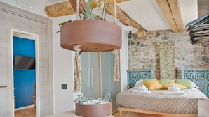 Une chambre moderne avec un lit, un pot de fleurs suspendu contenant des plantes et un plafond au style rustique.