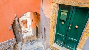 Une ruelle étroite avec une porte verte et une boîte aux lettres sur le côté droit.