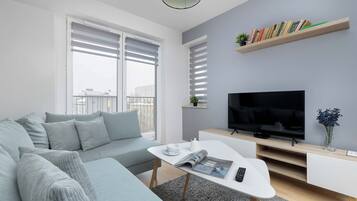 A modern living room with a sofa, coffee table, TV, and bookshelves.