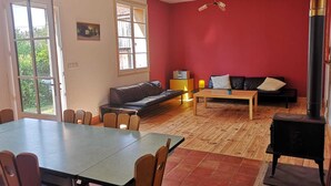 A living room with a red wall, a black sofa, a wooden table, and a black stove.