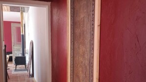 A narrow hallway with wooden flooring and a red wall.