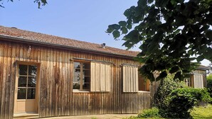 A rustic wooden building with a tiled roof, a large window, and a door.
