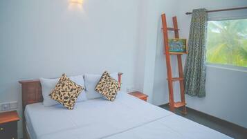 A bedroom with a bed, two pillows, a nightstand, a wall-mounted light, a ladder, and a window with a curtain.