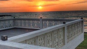 Un balcón con barandilla decorativa que da al atardecer sobre el mar.