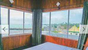 Una habitación con un amplio ventanal que ofrece vistas al mar y un pueblo lejano.