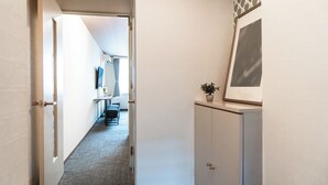 Ein Flur mit einer Tür, einem Schreibtisch mit Stühlen, einem Blumentopf und einem Schrank.