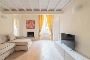 Ein Wohnzimmer mit einer Eckcouch, einem Flachbildfernseher, einem Kamin und einem großen Fenster mit gelben Vorhängen.