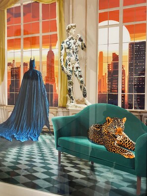 Ein Zimmer mit einem grünen Sofa, einer Leopardenstatue und einer Batman-Figur.