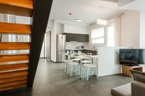 Eine moderne Küche mit weißen Schränken, einem Kühlschrank und einem Essbereich mit Tisch und Stühlen.