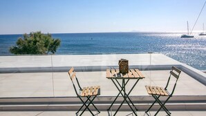 Una terraza con una mesa y dos sillas, con vista a un cuerpo de agua con veleros.