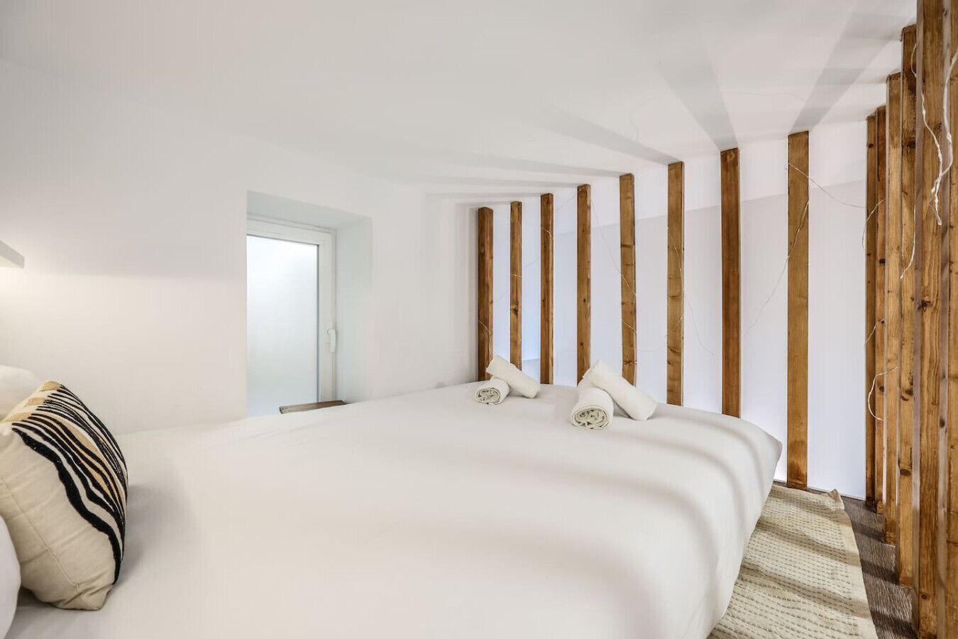 Een slaapkamer met een groot bed, houten lambrisering en een deur.