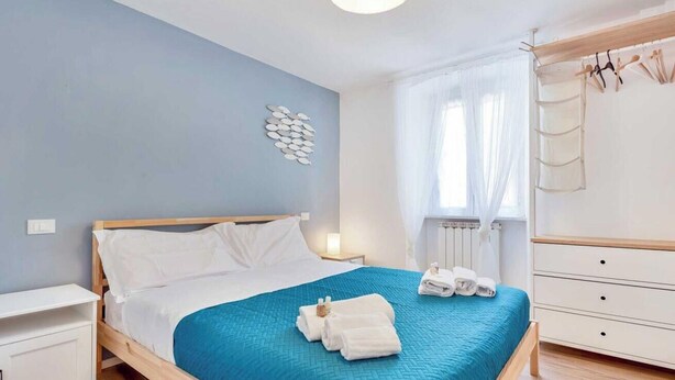 Une chambre à coucher comprenant un lit, une table de chevet, une armoire et une fenêtre avec des rideaux.
