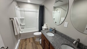 Uma casa de banho moderna com chuveiro, sanita e lavatório.