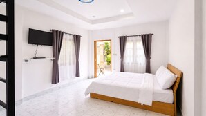 Une chambre avec un lit, un téléviseur fixé au mur et une porte donnant sur un espace extérieur.