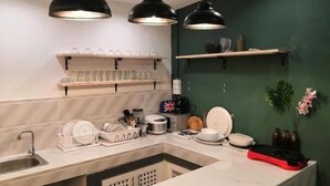 Une cuisine moderne avec un plan de travail en marbre, des suspensions noires et un mur d’accent vert.