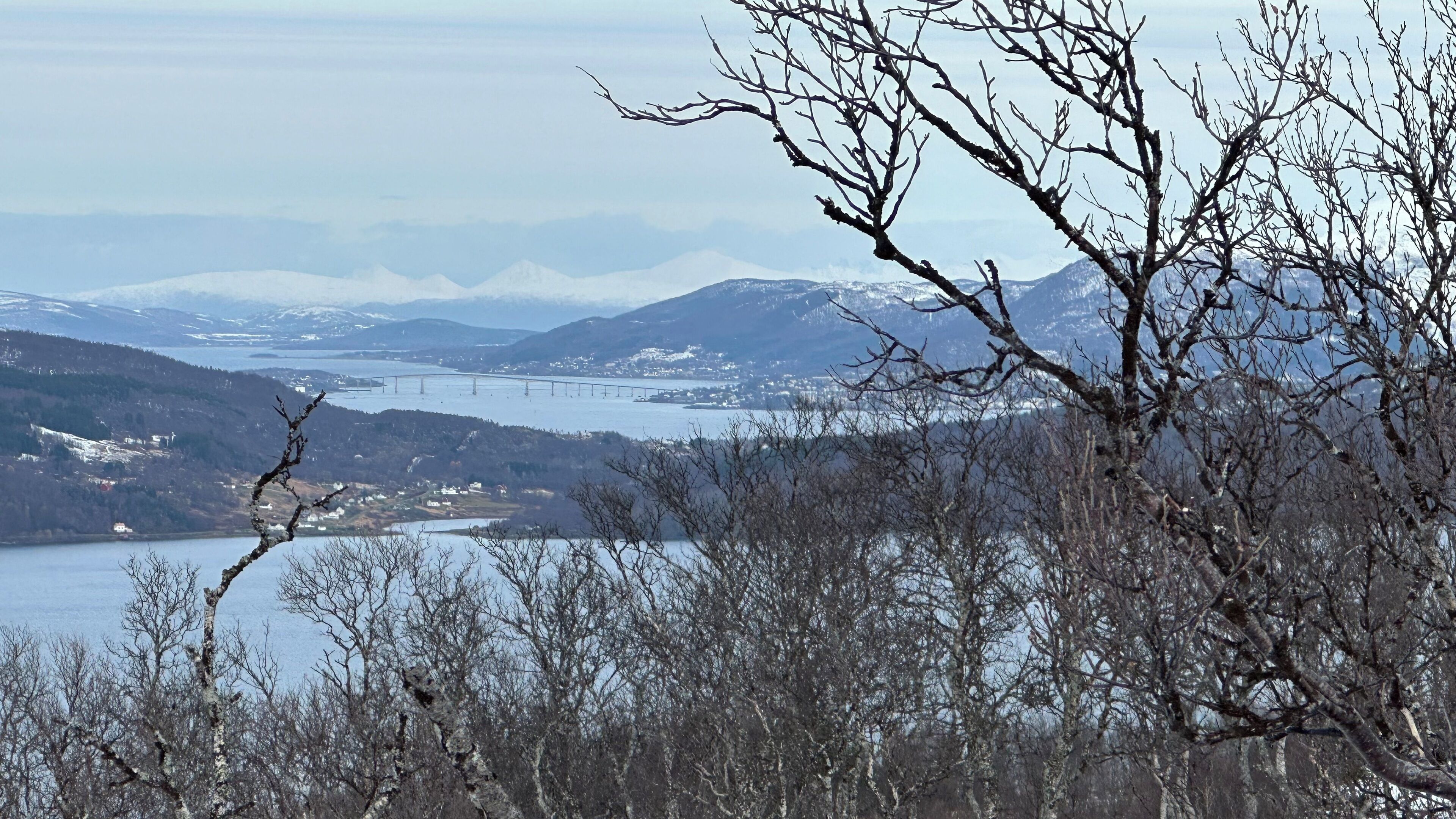 A mountainous landscape with a lake and a bridge.
