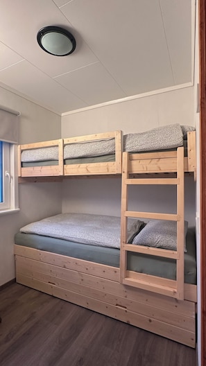 A bunk bed with a ladder, wooden headboard, and a window with blinds.