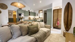 A cozy living room with a sofa, a dining area with a table, and a kitchen in the background. - House between forest & beach on foot • Nordic bath (Jard-sur-Mer)