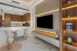 Eine moderne Küche mit großem Fernseher, Marmorarbeitsplatten und Holzschränken.