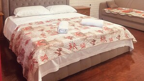 Ein Schlafzimmer mit Bett, Nachttisch, Sofa und einer Ziegelwand.