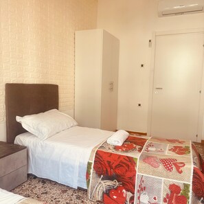 A bedroom with a bed, a nightstand, a wardrobe, and a door.