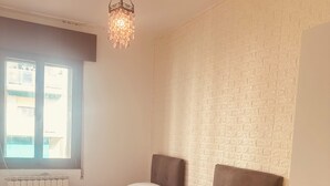 Quarto com duas camas, um radiador, uma janela e parede com textura.