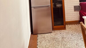 Uma cozinha compacta com geladeira, relógio e armário de madeira.