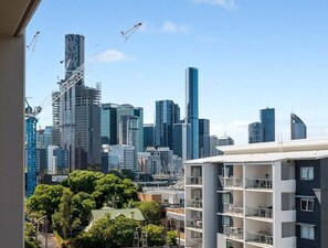 A cityscape with modern high-rise buildings, a construction crane, and a residential building with balconies. - Modern 1BR City-Fringe Stay with Balcony Views (Brisbane)