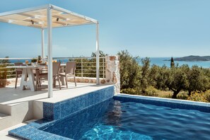 Zona junto a la piscina con pérgola, asientos y vista al mar.