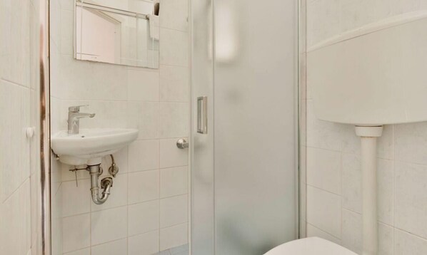 Ein Badezimmer mit einem weißen Waschbecken, einem Spiegel und einer Toilette.