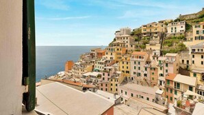 A coastal town with colorful buildings, a clear view of the sea, and a prominent green structure on the left.