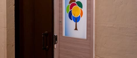 Una puerta con un panel de vidrio esmerilado que muestra un árbol colorido y el texto 'Room 1'.